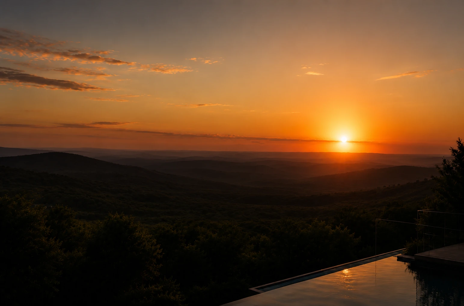 Hill Country views from a stone terrace and infinity pool at sunset